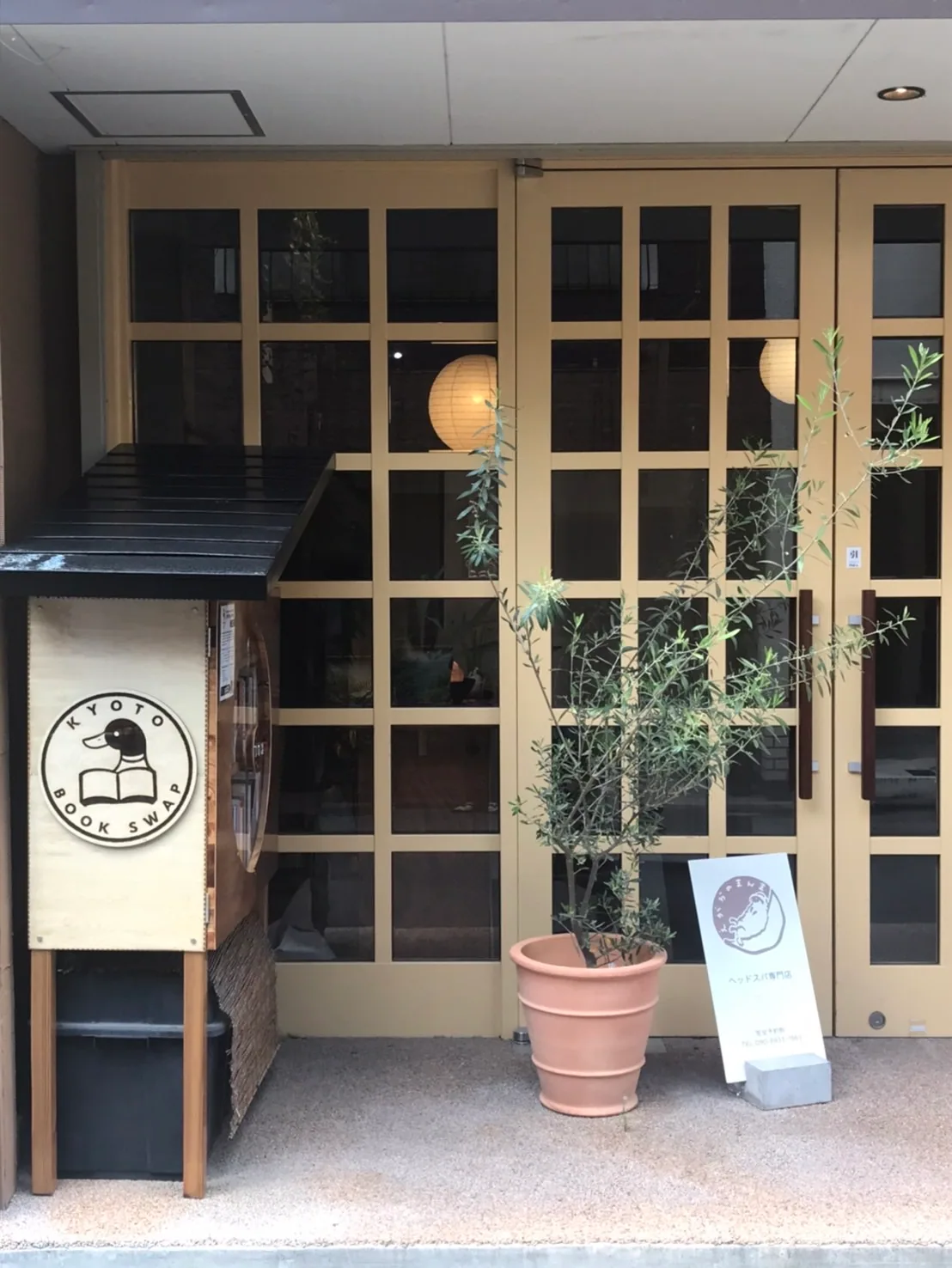 Entrance of a building in Kyoto with a book shop sign and potted tree