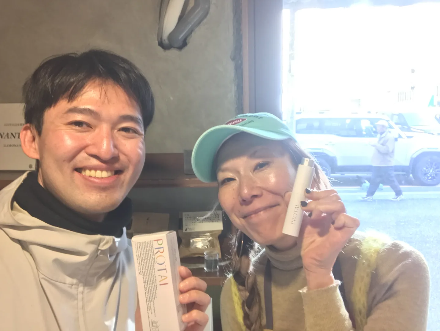 Two people displaying PROTAI products at a café