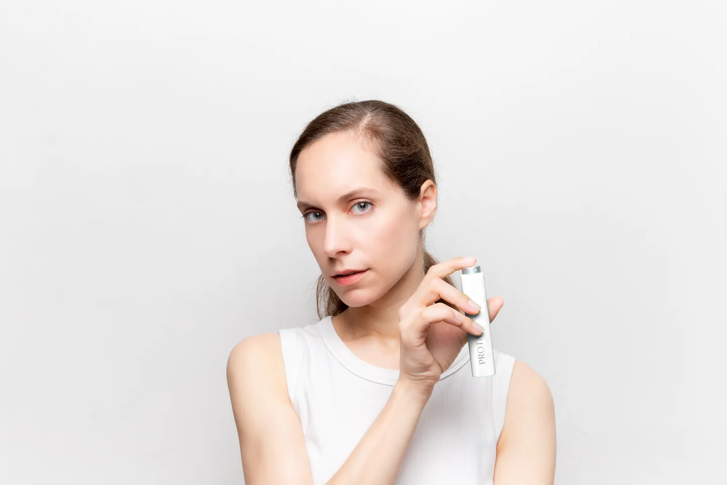 Woman holding a PROTAI bottle against a light background